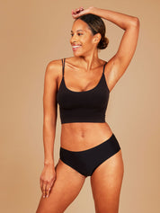 Woman smiling radiantly while wearing black seamless period underwear.