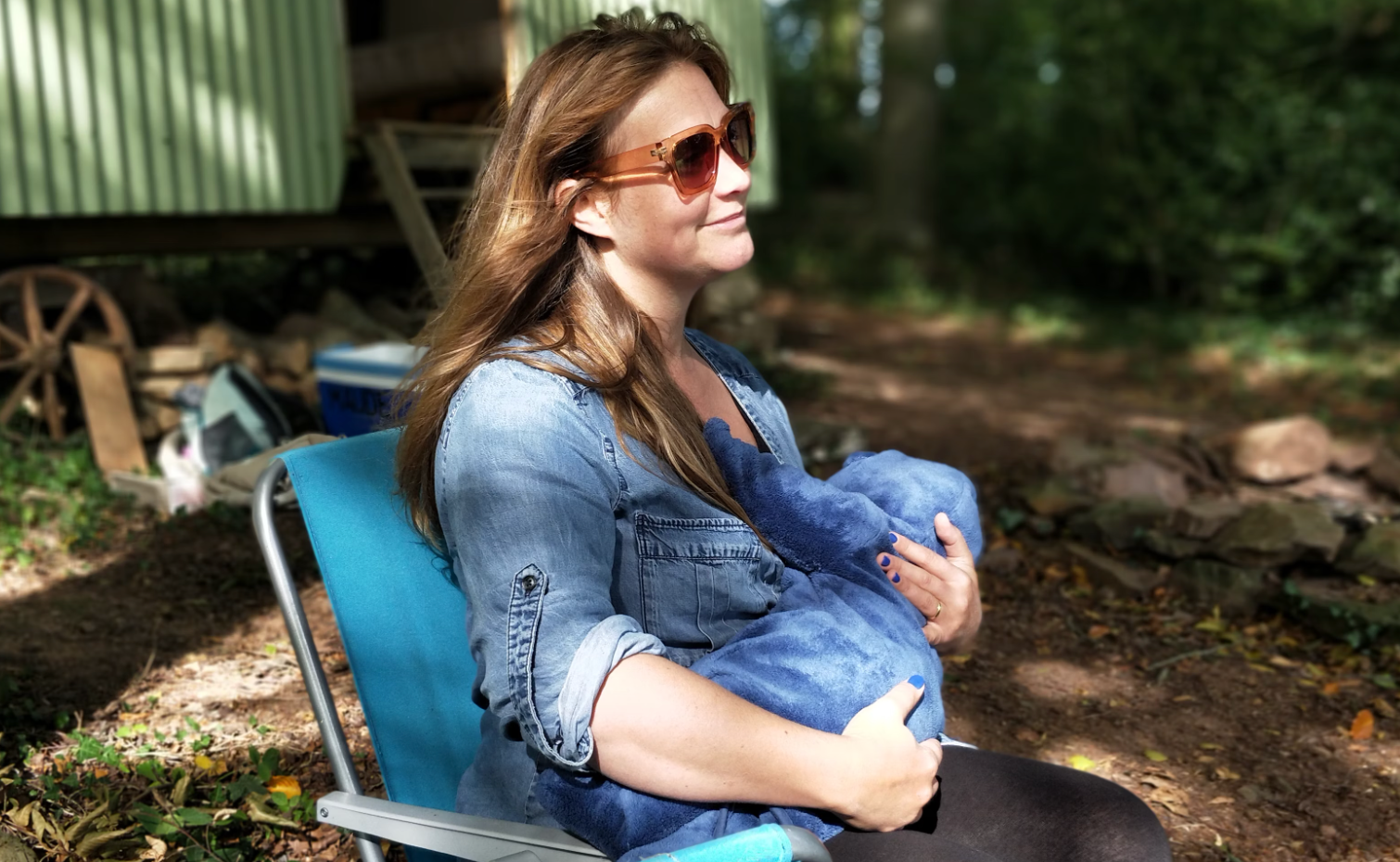 A mother sitting outdoors and breastfeeding her baby, enjoying a calm and peaceful moment.