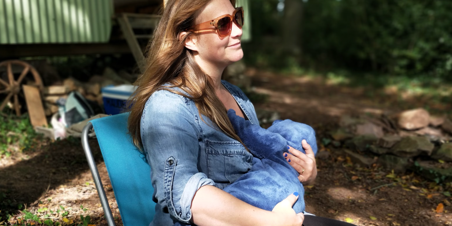 A mother sitting outdoors and breastfeeding her baby, enjoying a calm and peaceful moment.